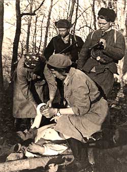 Врач П. Михайленко оказывает помощь раненому партизану. 1943 г.